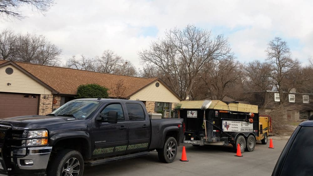 Pickup truck and trailer parked outside a home with construction materials visible.