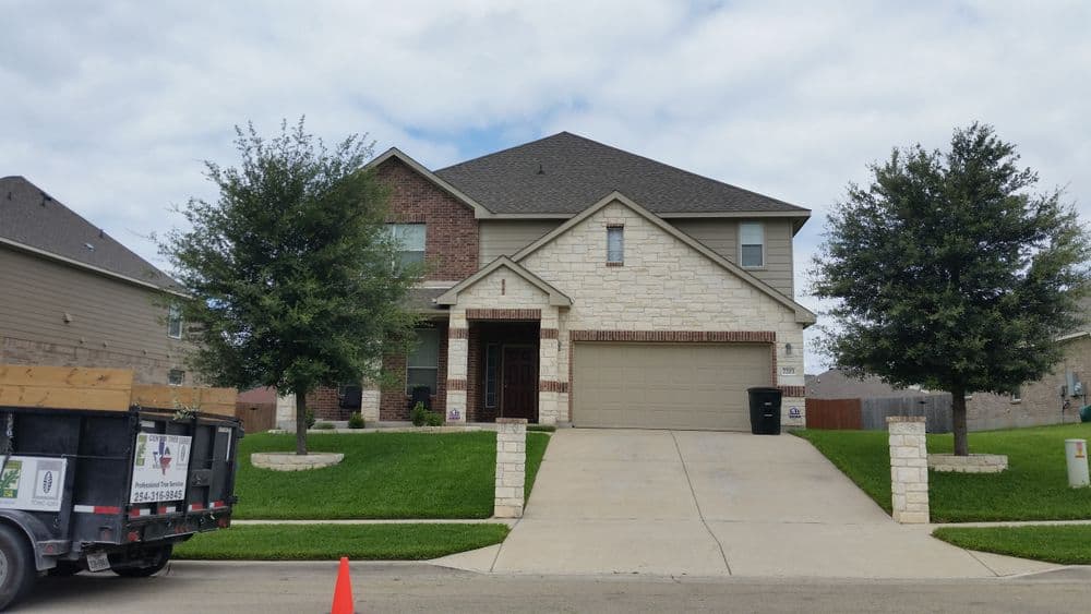 Modern two-story house with stone accents, green lawn, and concrete driveway.
